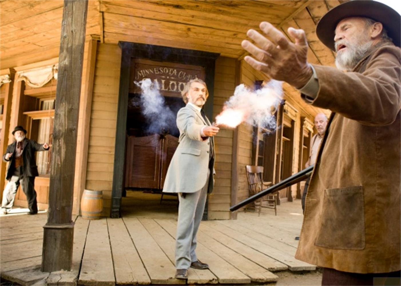 Duel dans le Far West devant un saloon. Un homme tire avec un pistolet.