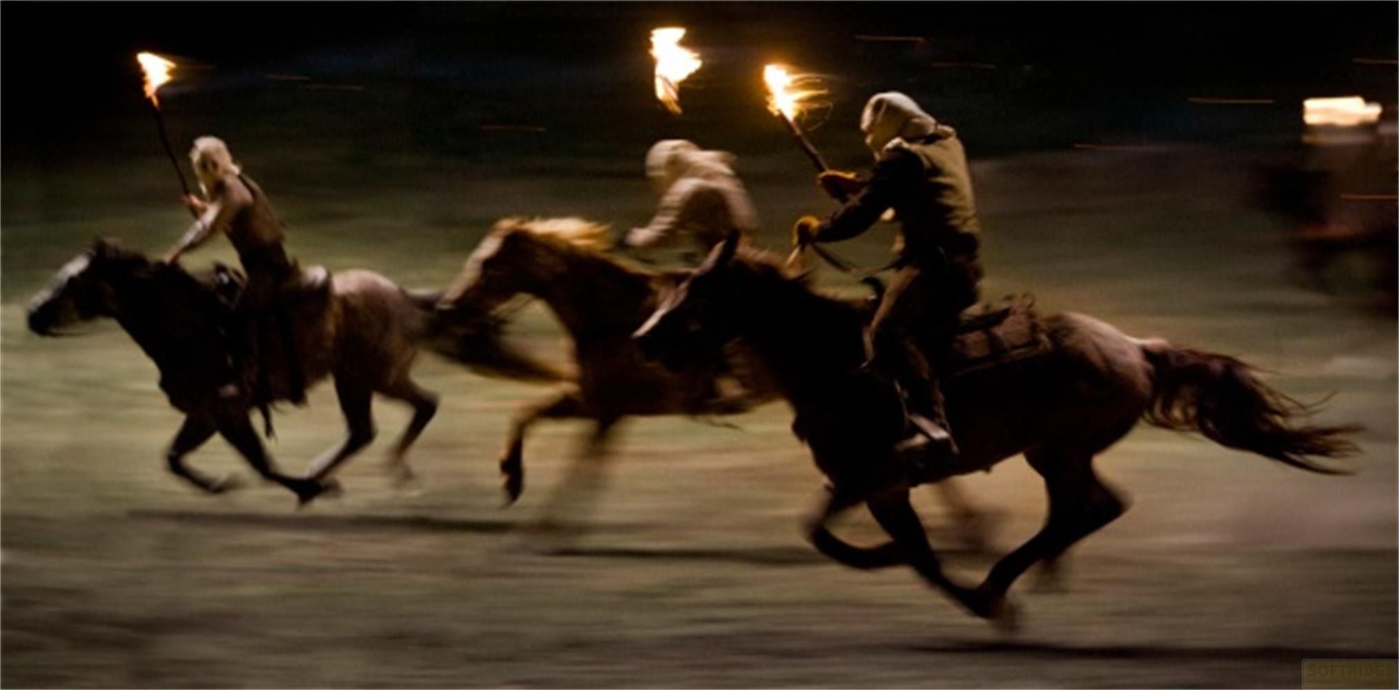 Trois cavaliers tenant des torches galopent dans un champ la nuit.