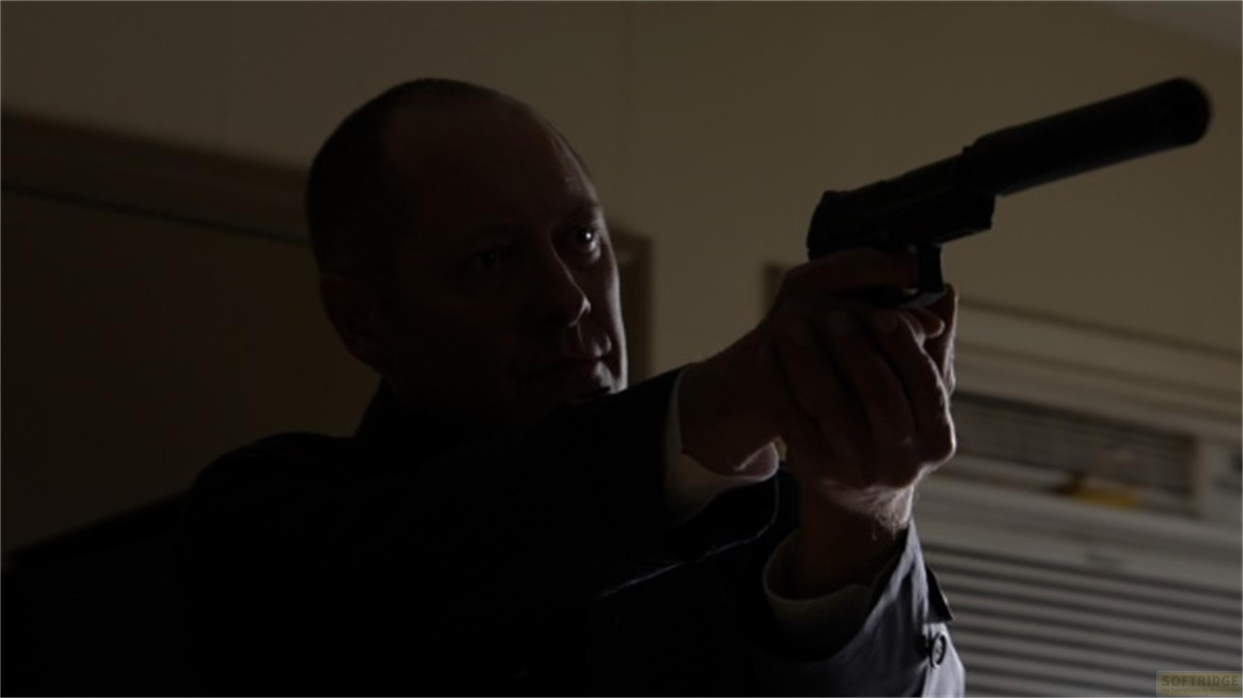 Un homme en costume sombre vise un pistolet silencieux.