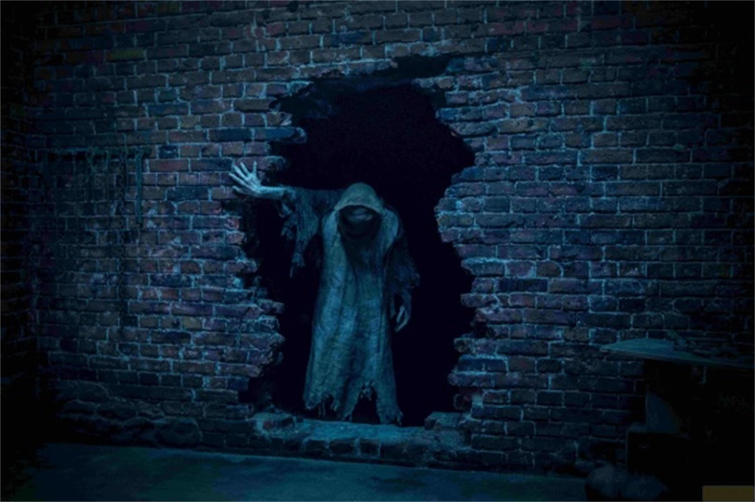 Un fantasma con cappuccio attraversa un buco in un muro di mattoni.
