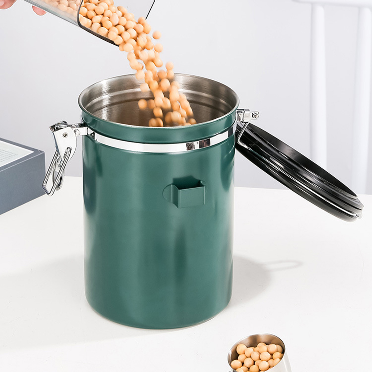Bohnen werden in einen grünen Metallbehälter gefüllt. Ein kleiner Löffel liegt daneben.