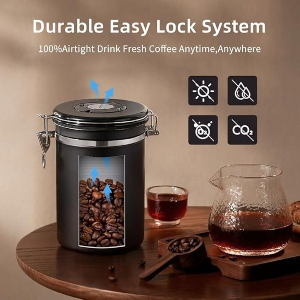 Schwarzer Kaffeebehälter mit Kaffeebohnen und Zubehör auf einem Holztisch.