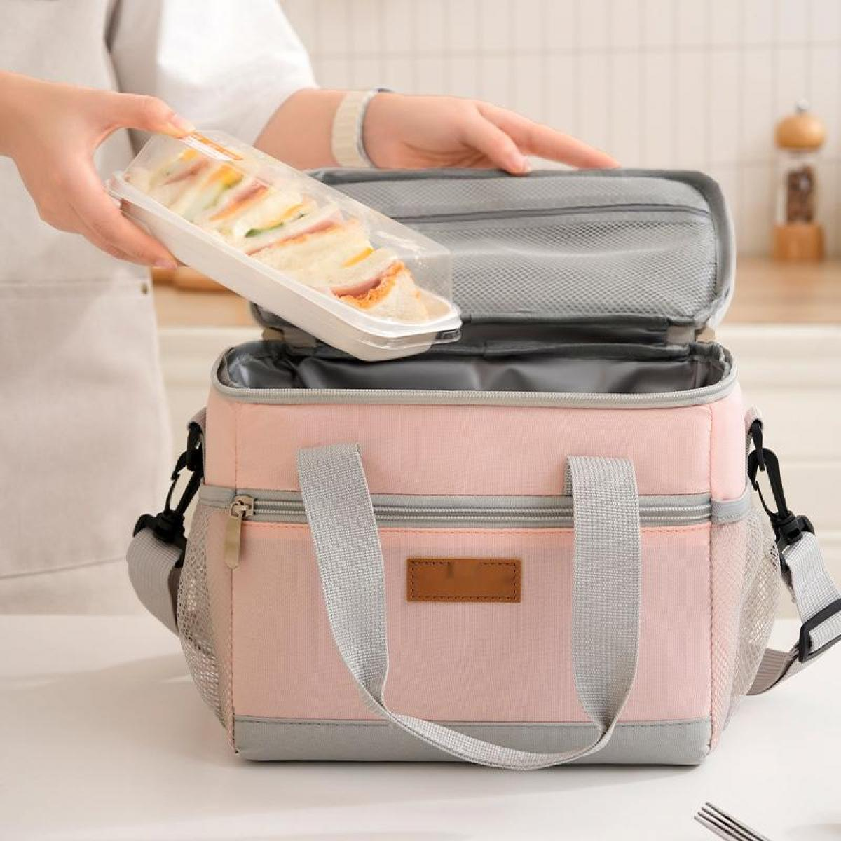 Eine Hand legt eine Sandwichbox in eine rosa Kühltasche.