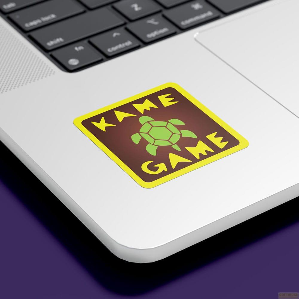 Ein Aufkleber mit einer Schildkröte und den Wörtern KAME GAME auf einem Laptop.