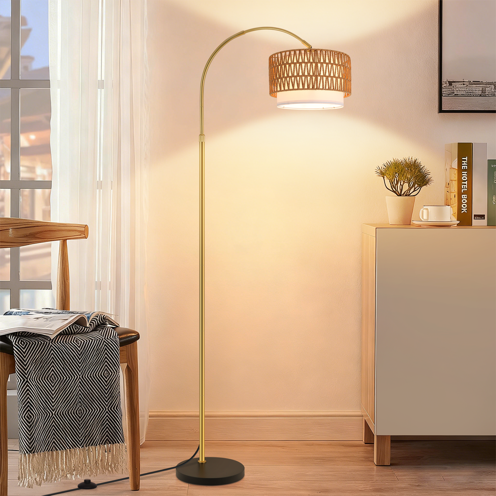 Una lampada ad arco dorata con paralume intrecciato sopra un paralume in tessuto bianco.