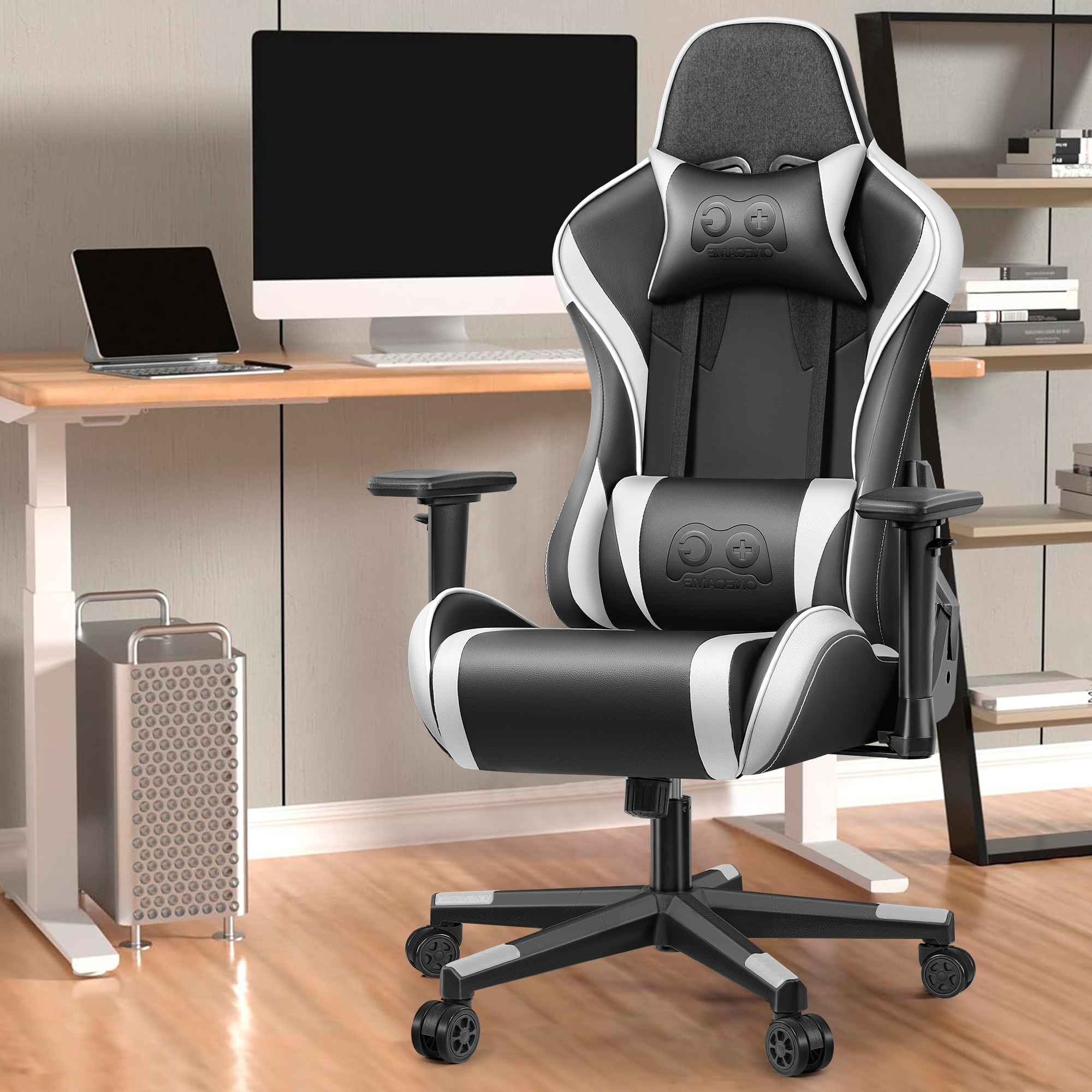 Ein schwarzer und weißer Gaming-Stuhl steht vor einem Schreibtisch mit Computer und Laptop.