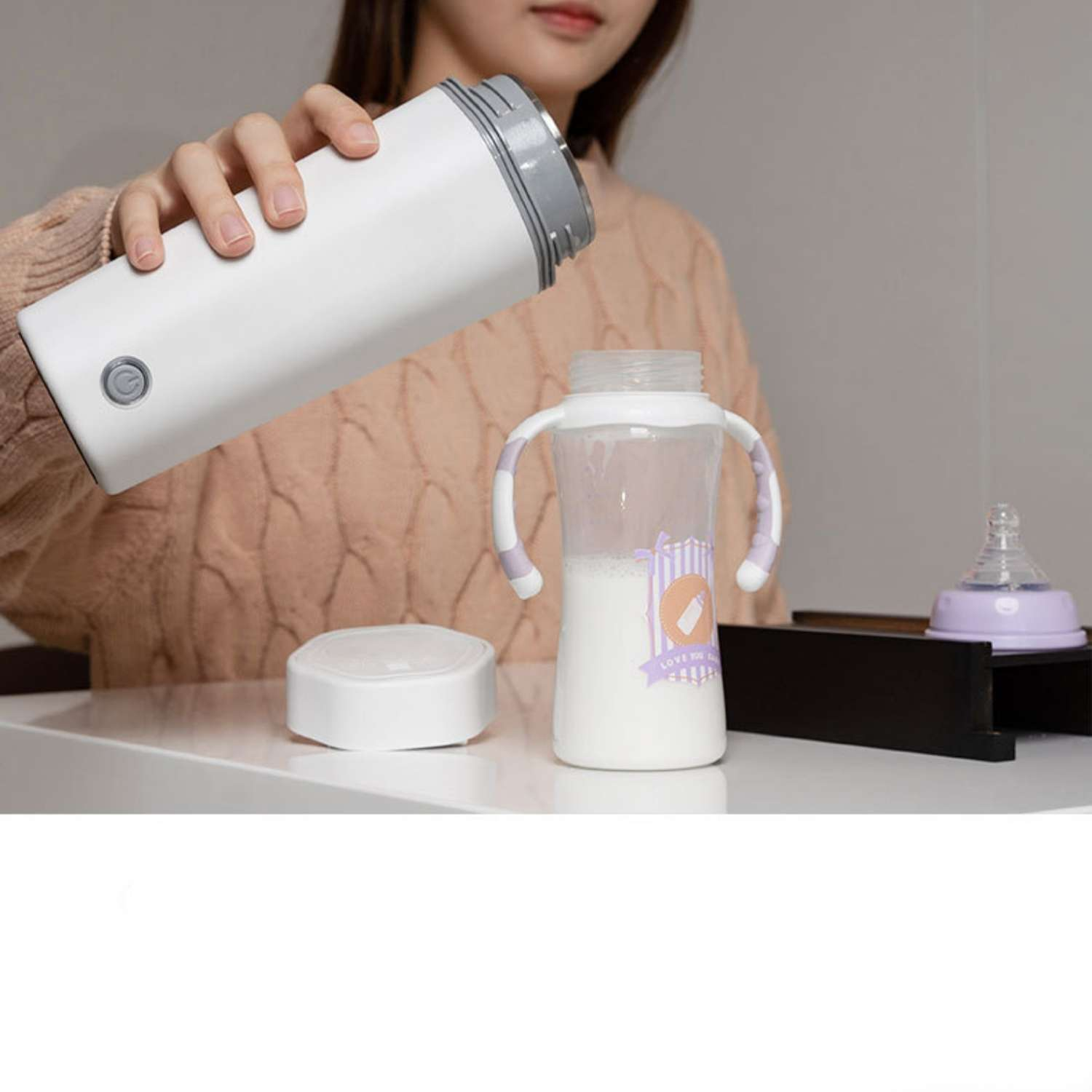 Eine Person gießt Flüssigkeit aus einem weißen Behälter in eine Babyflasche.