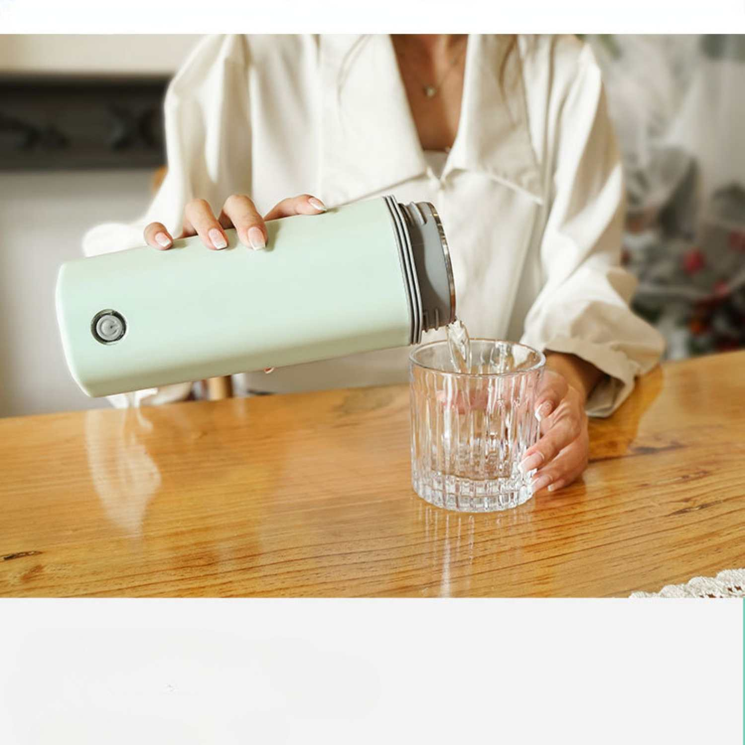 Eine Person gießt Wasser aus einem hellgrünen Behälter in ein Glas.
