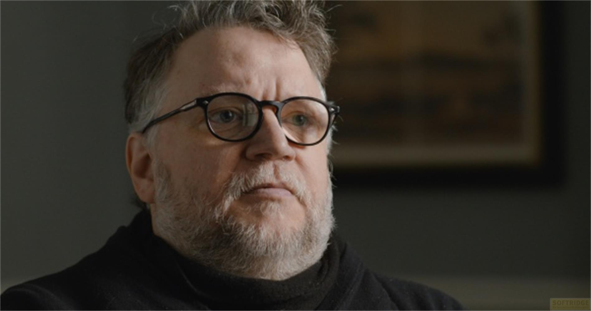 Un uomo con occhiali e barba grigia indossa un top nero.