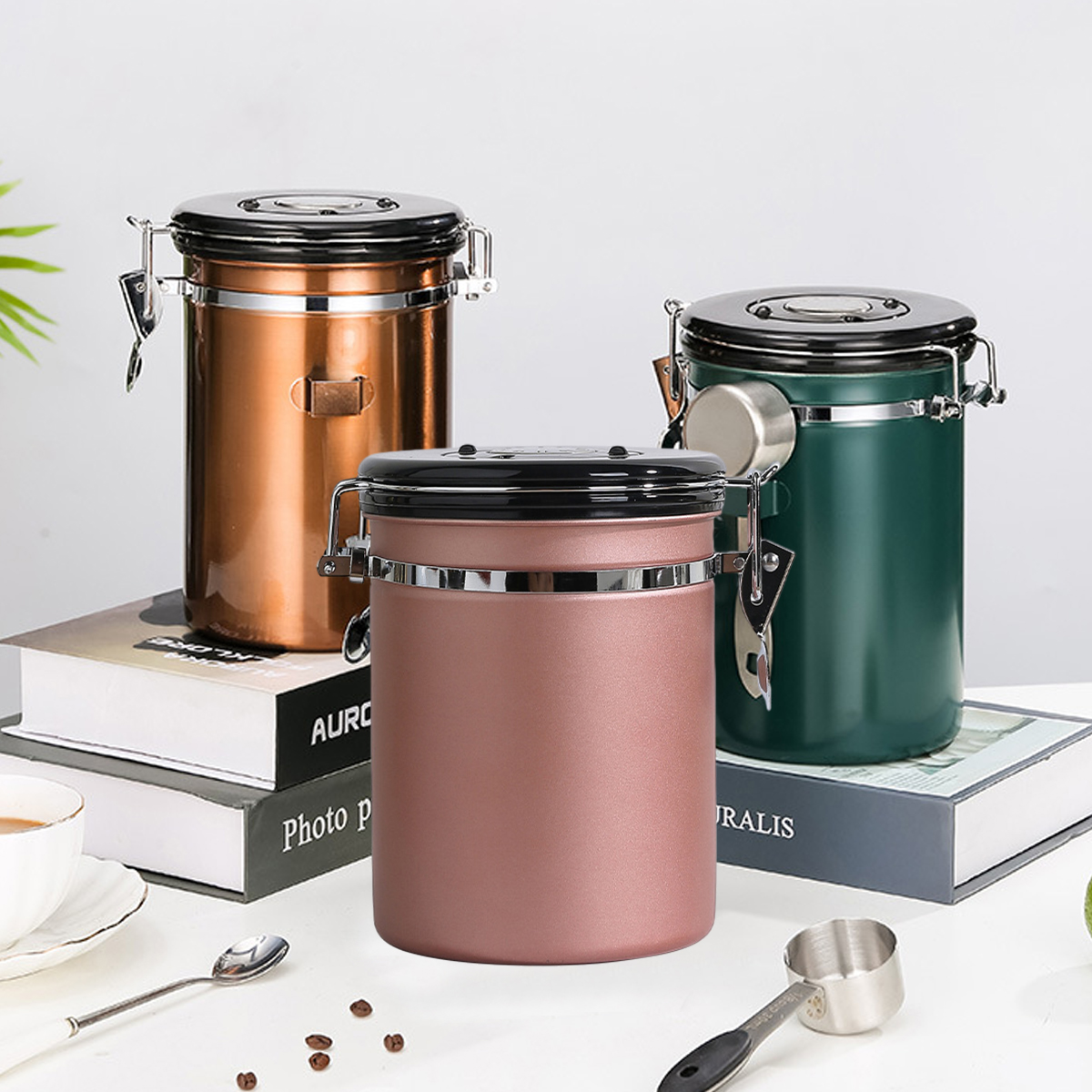 Drei runde Vorratsdosen aus Metall in Kupfer, Rosé und Grün mit schwarzen Deckeln.