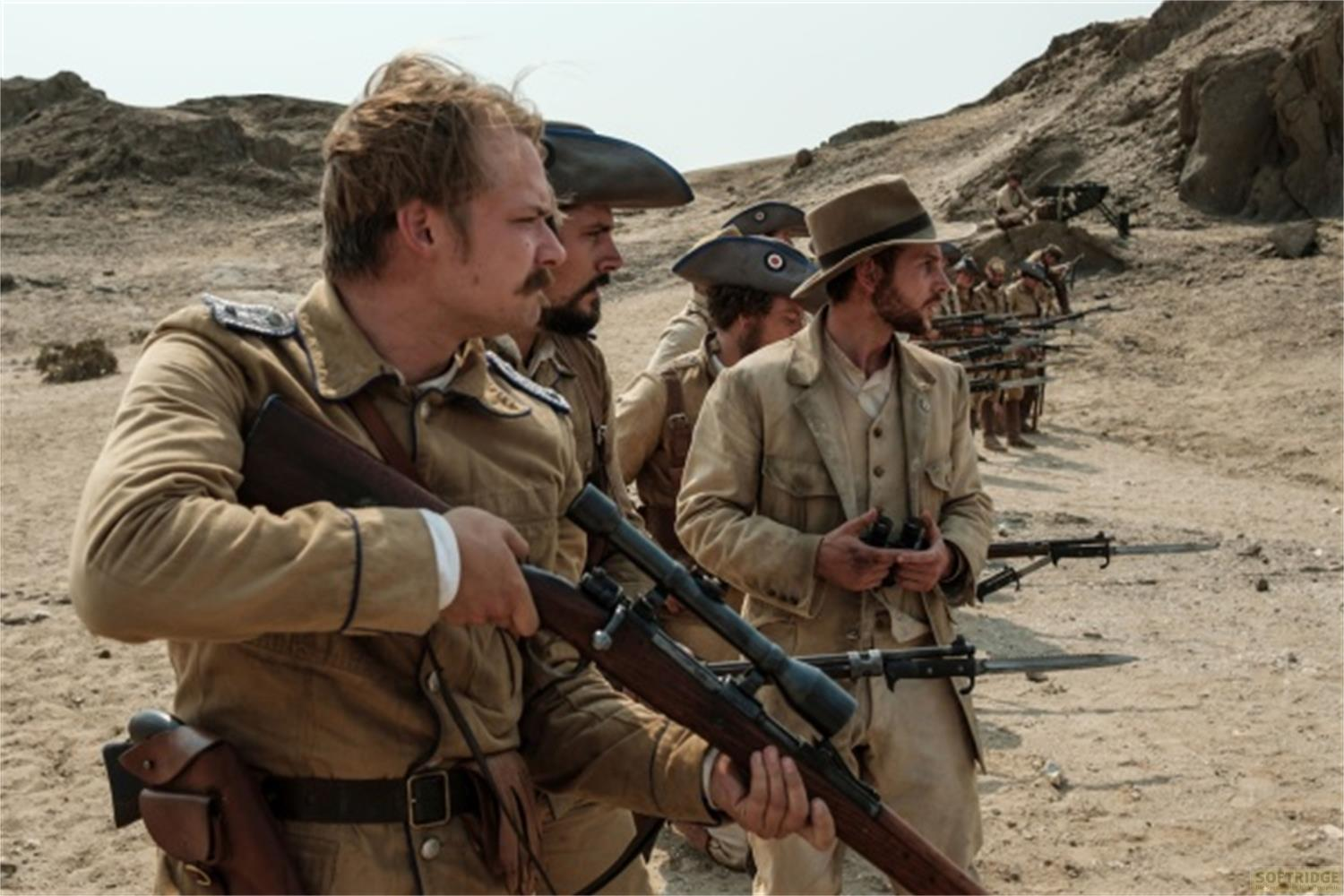 Uomini in uniforme con fucili stanno in un paesaggio desertico.