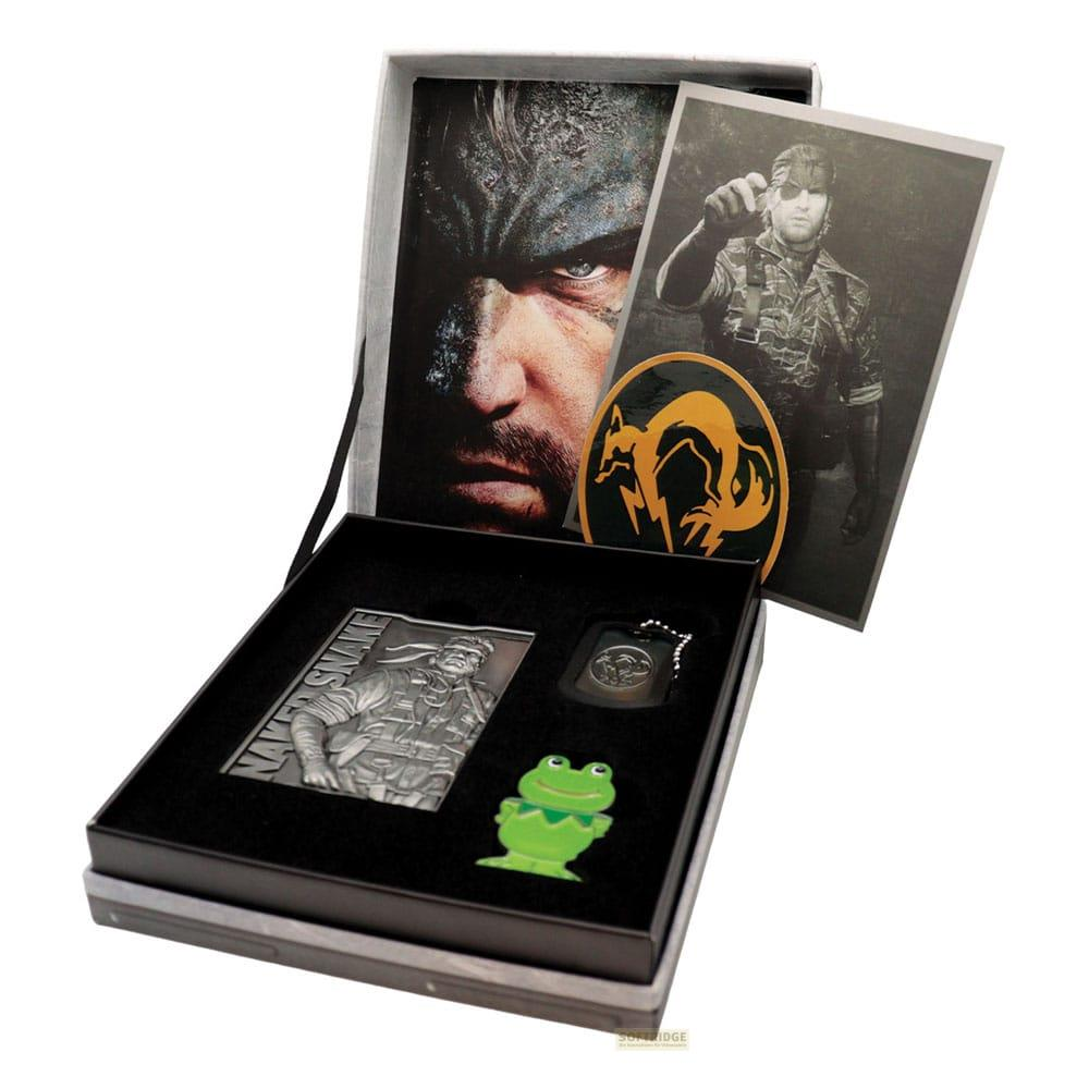 Caja abierta con lata de metal, insignia y figura de rana.
