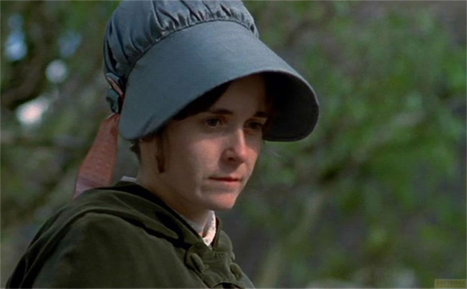 Una donna con cappello blu e vestiti verdi all'aperto.