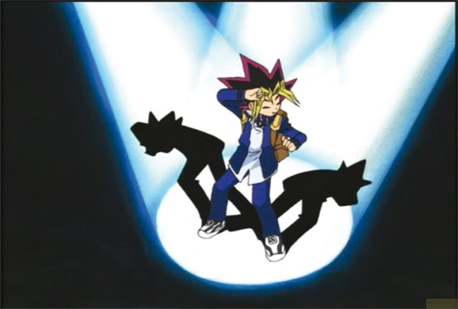 Yugi Muto in scena con due ombre. Giacca blu, zaino.