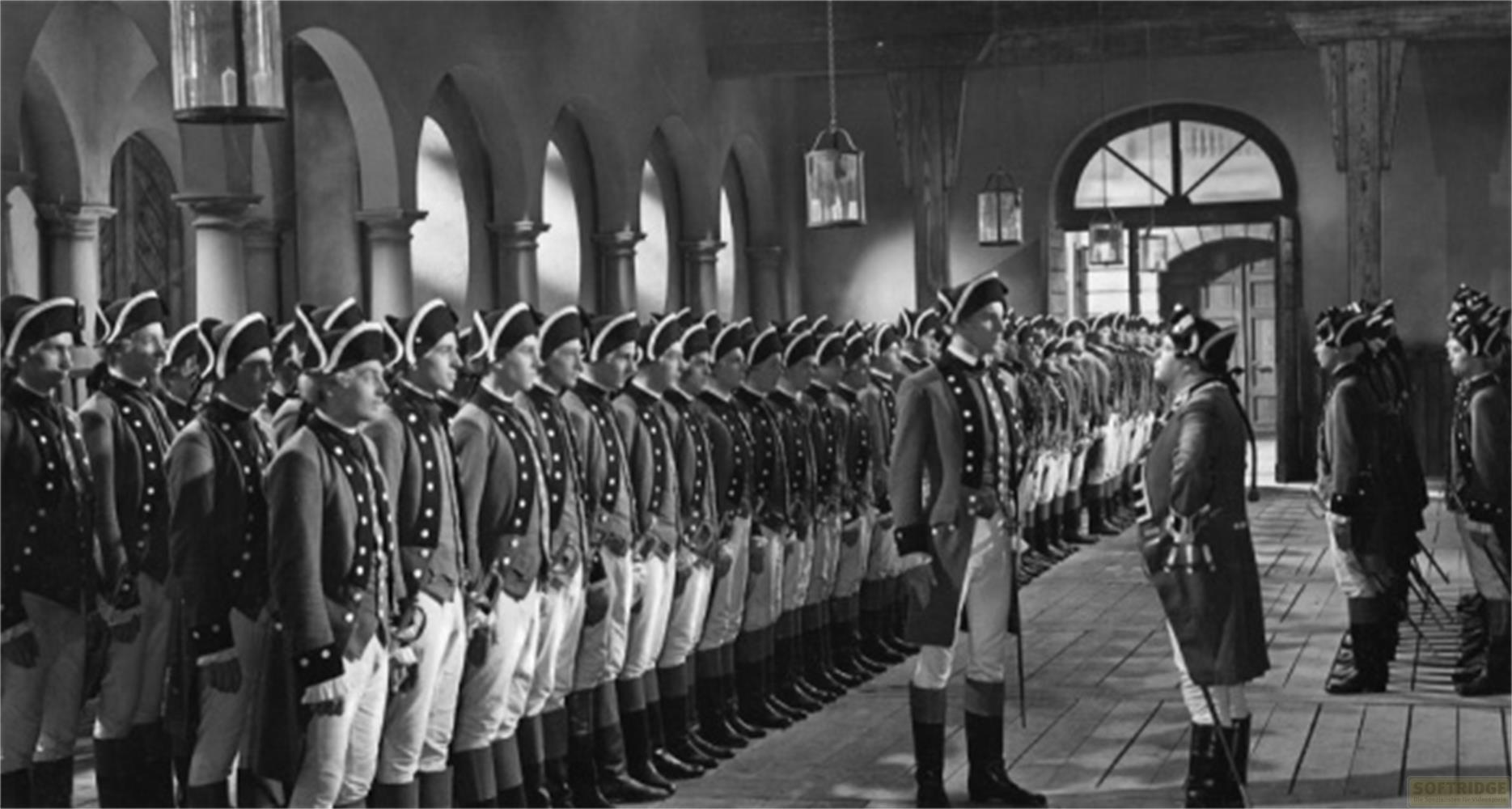 Soldati in uniforme in file in un interno con architettura ad arco.
