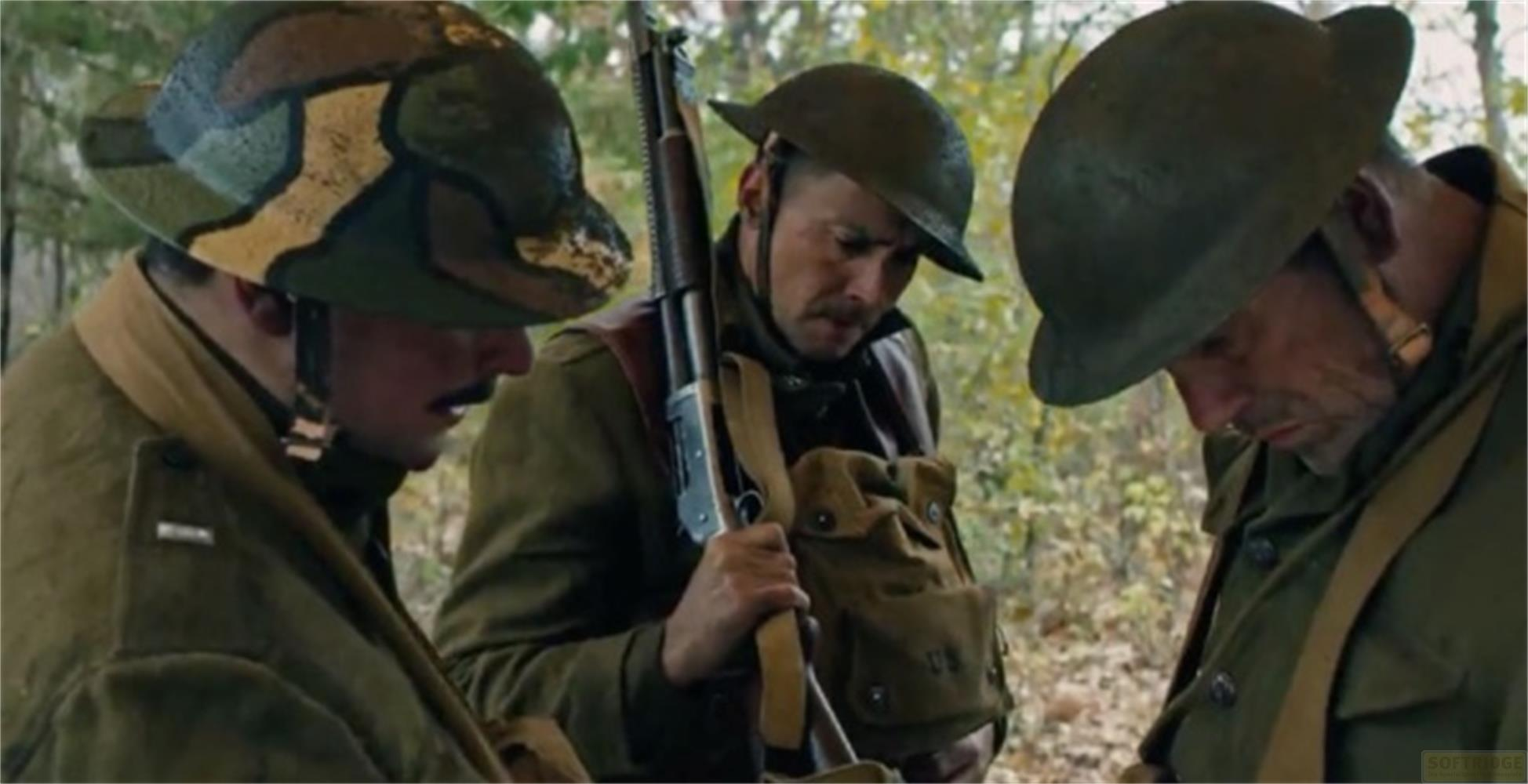 Tre soldati in uniforme con elmetti e fucili stanno nel bosco.