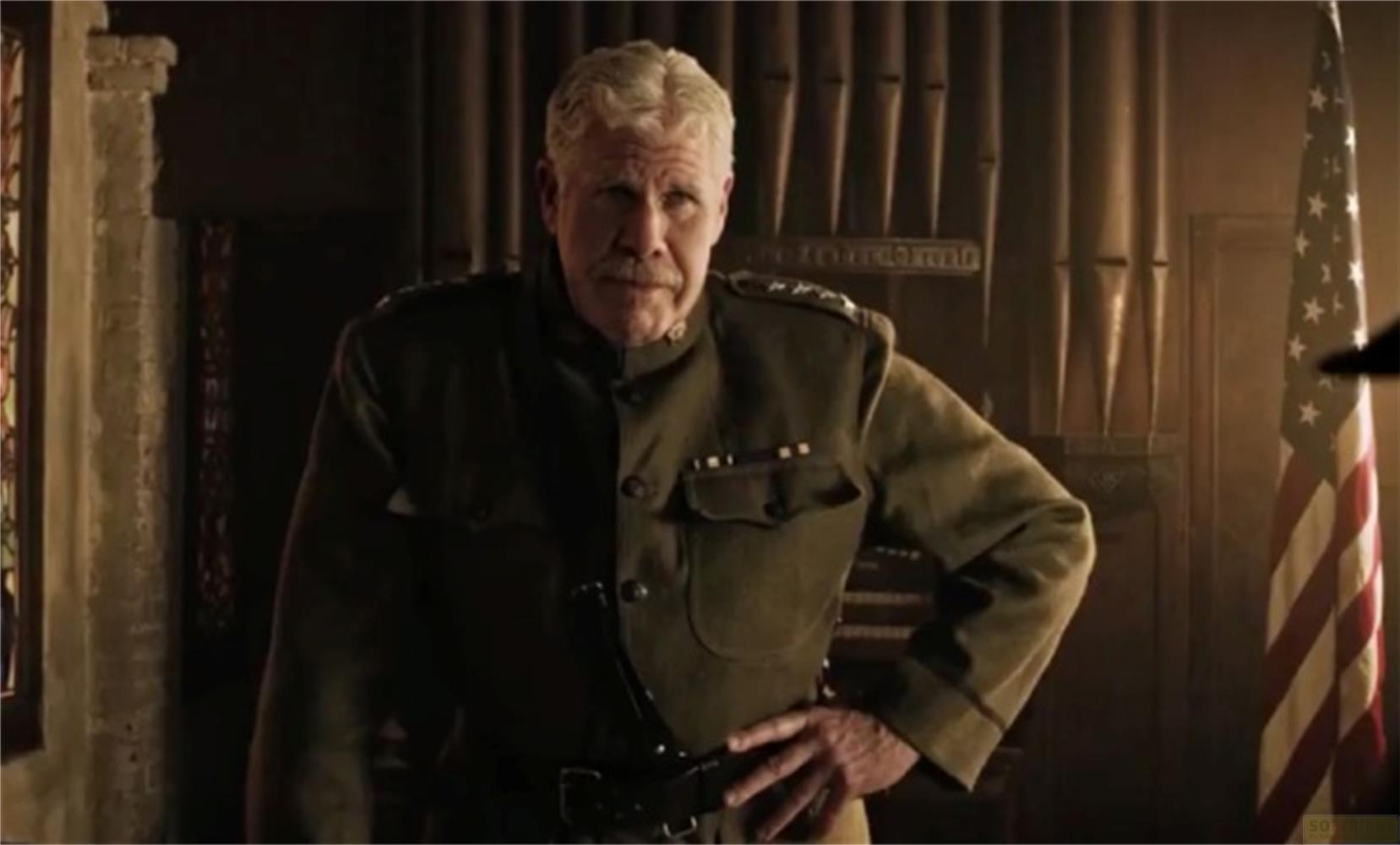 Un uomo in uniforme sta davanti a un organo e a una bandiera americana.