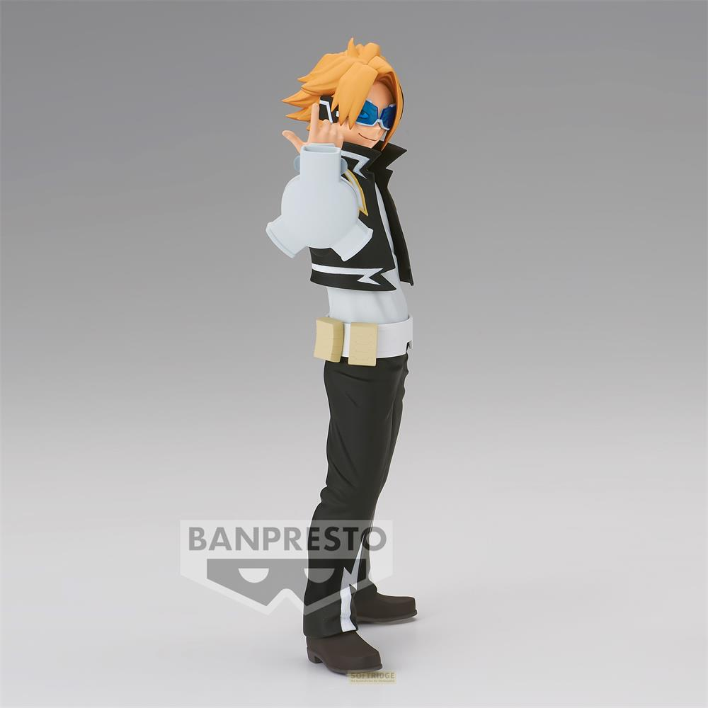 Una figura con pelo rubio, gafas azules, chaleco negro y camisa blanca.