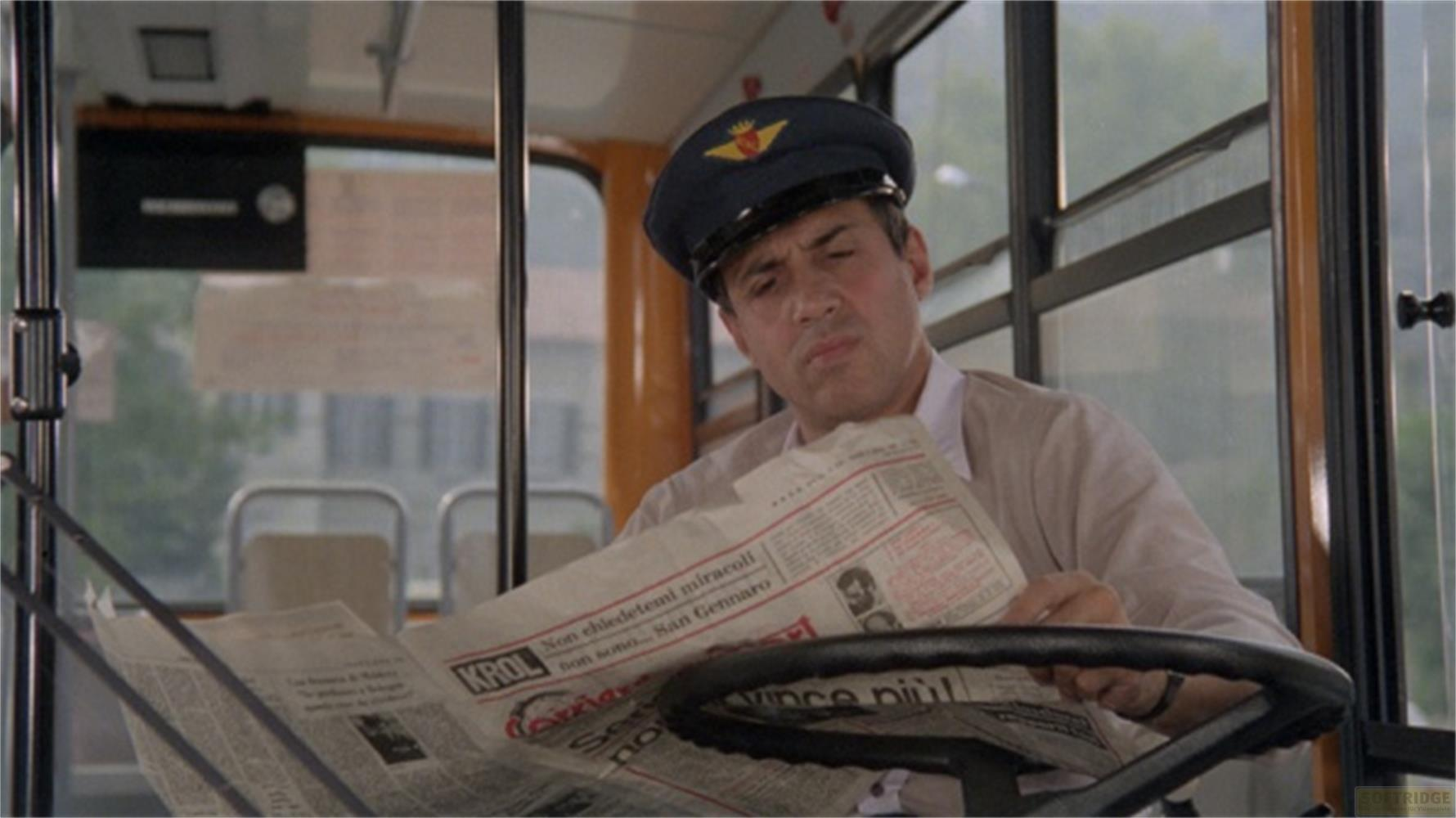 Un homme en uniforme lit un journal au volant d'un bus.