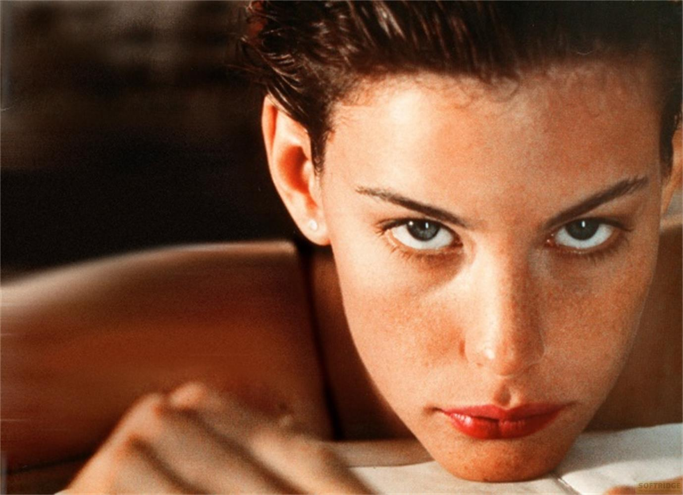 Primo piano di un volto, occhi blu, labbra rosse, capelli scuri.