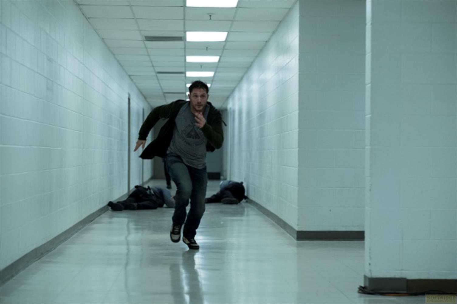 Un uomo corre lungo un corridoio, due giacciono a terra.