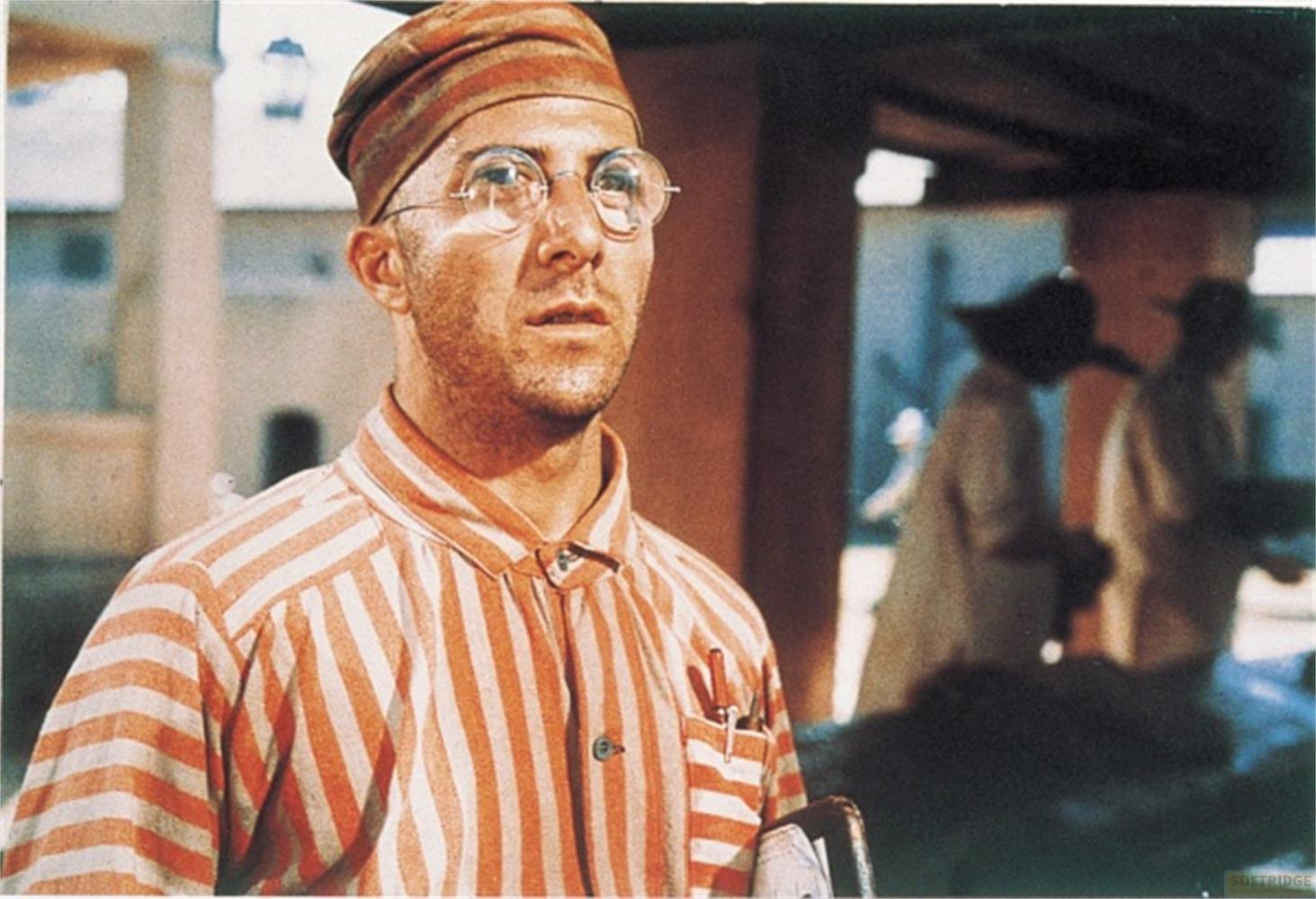 Uomo in uniforme a righe arancioni e bianche e berretto, con occhiali.