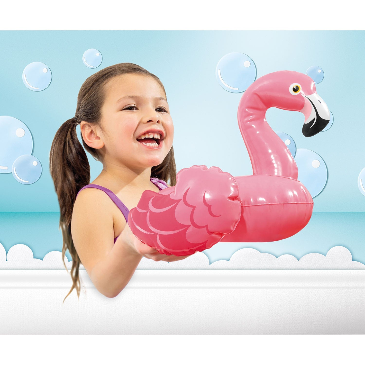 Una niña con coletas sostiene un flamenco inflable rosa en un baño.