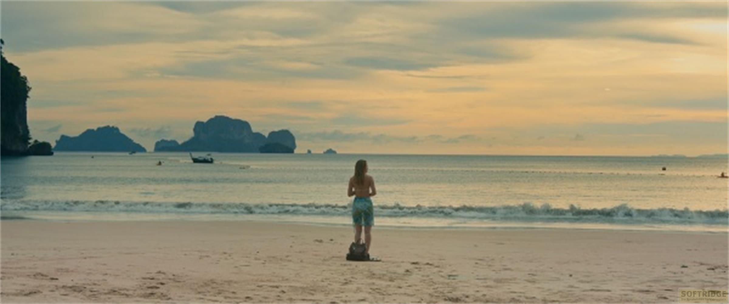 Donna sulla spiaggia guarda il mare e le isole al tramonto.