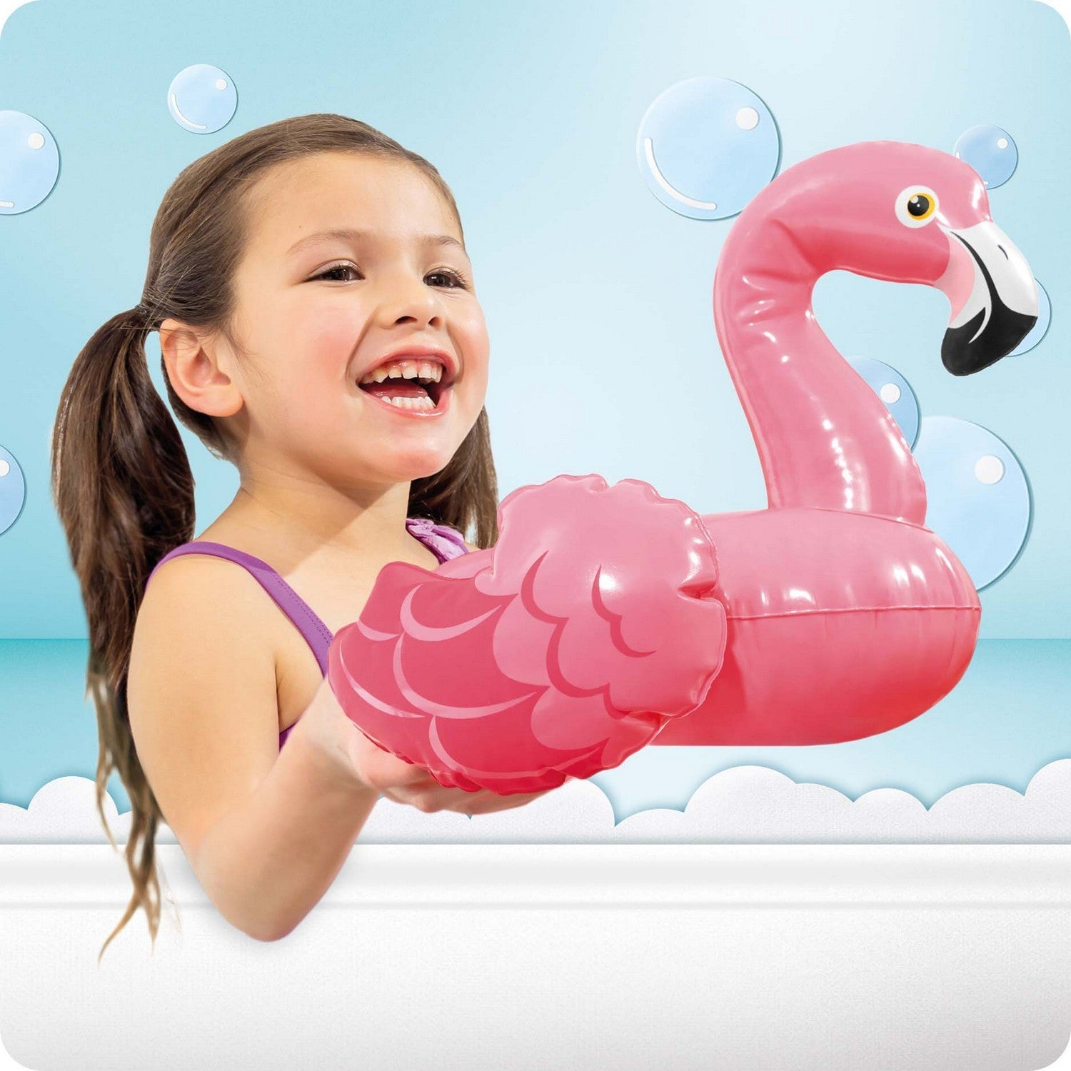 Una niña con coletas sostiene un flamenco inflable rosa en un baño.