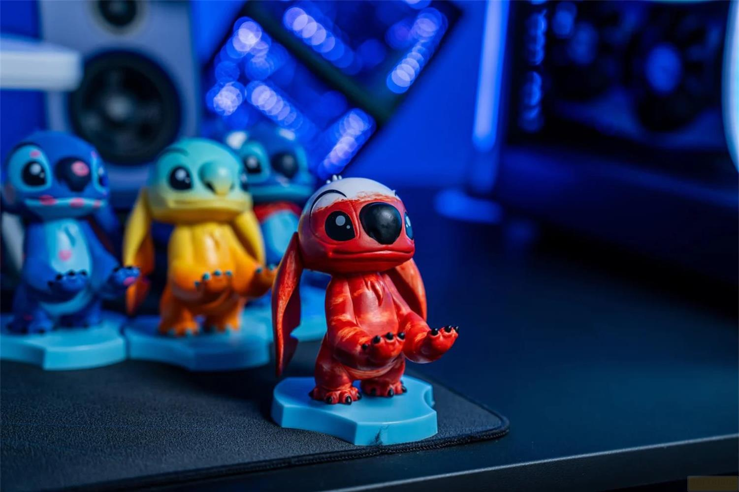 Quattro figure di Stitch di colori diversi si trovano una accanto all'altra su basi blu.