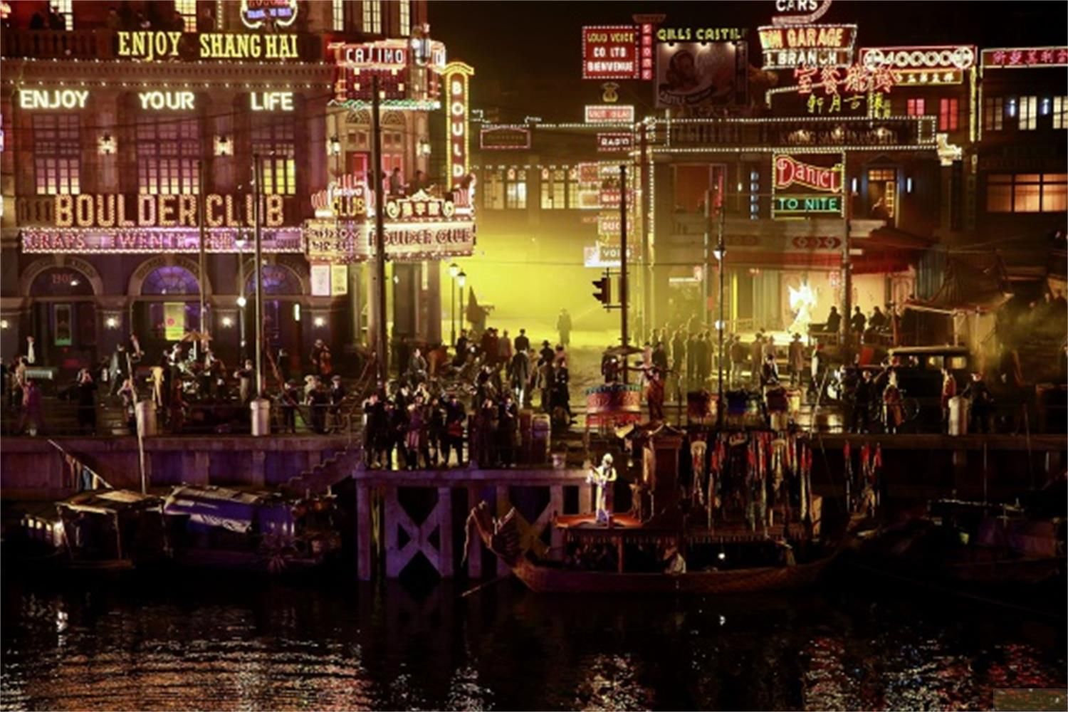 Scena notturna di una vivace città portuale con molte luci e persone.