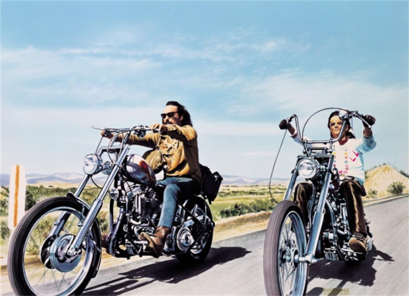 Deux hommes sur des motos chopper roulent sur une route dans un paysage sec.