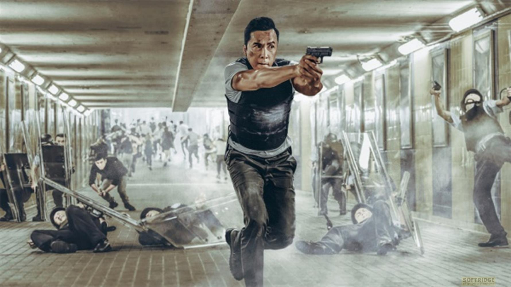 Un uomo con una pistola in un vicolo pieno di gente. Alcuni sono a terra.
