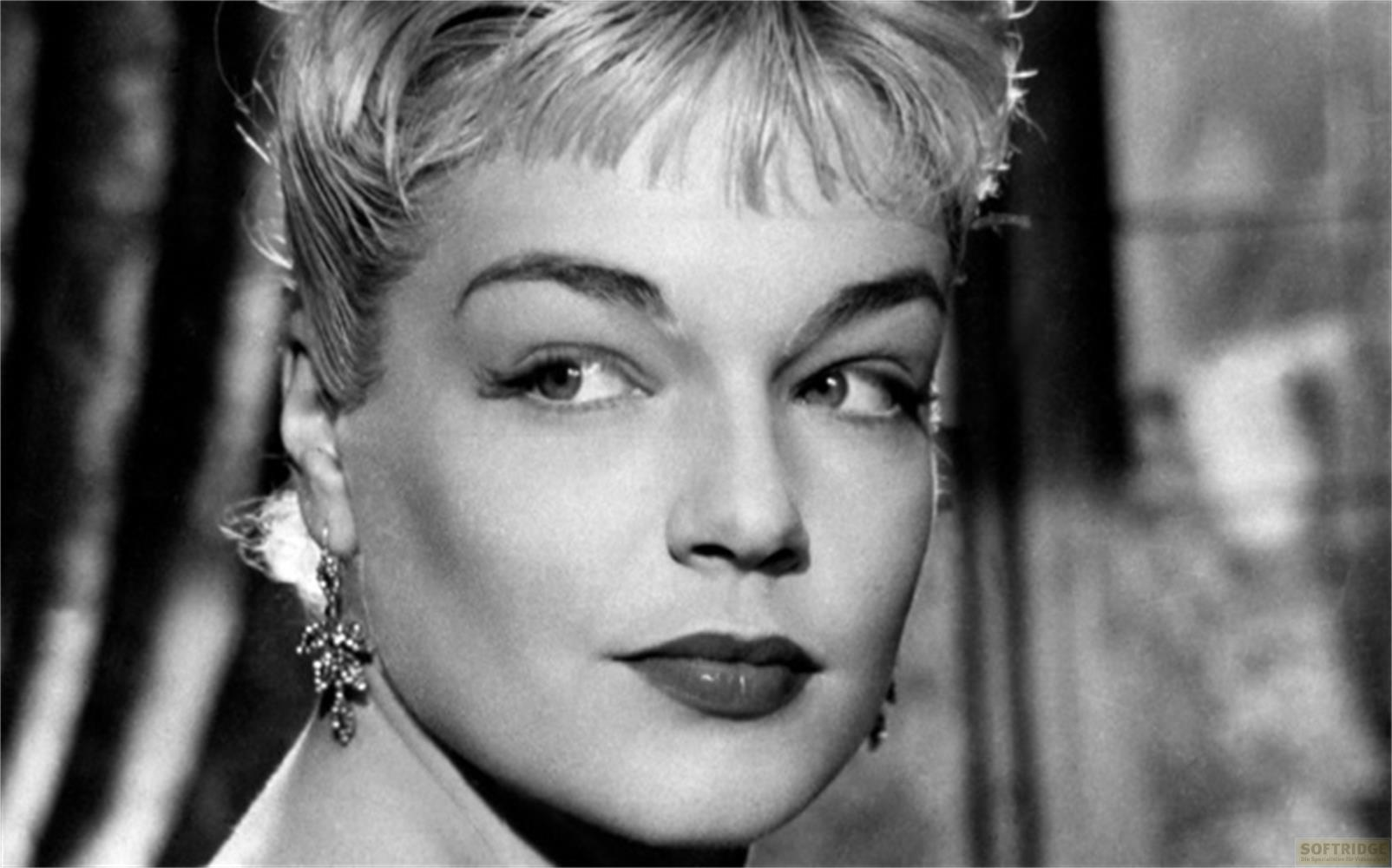 Ritratto in bianco e nero di una donna con capelli biondi pettinati all'indietro e orecchini vistosi.