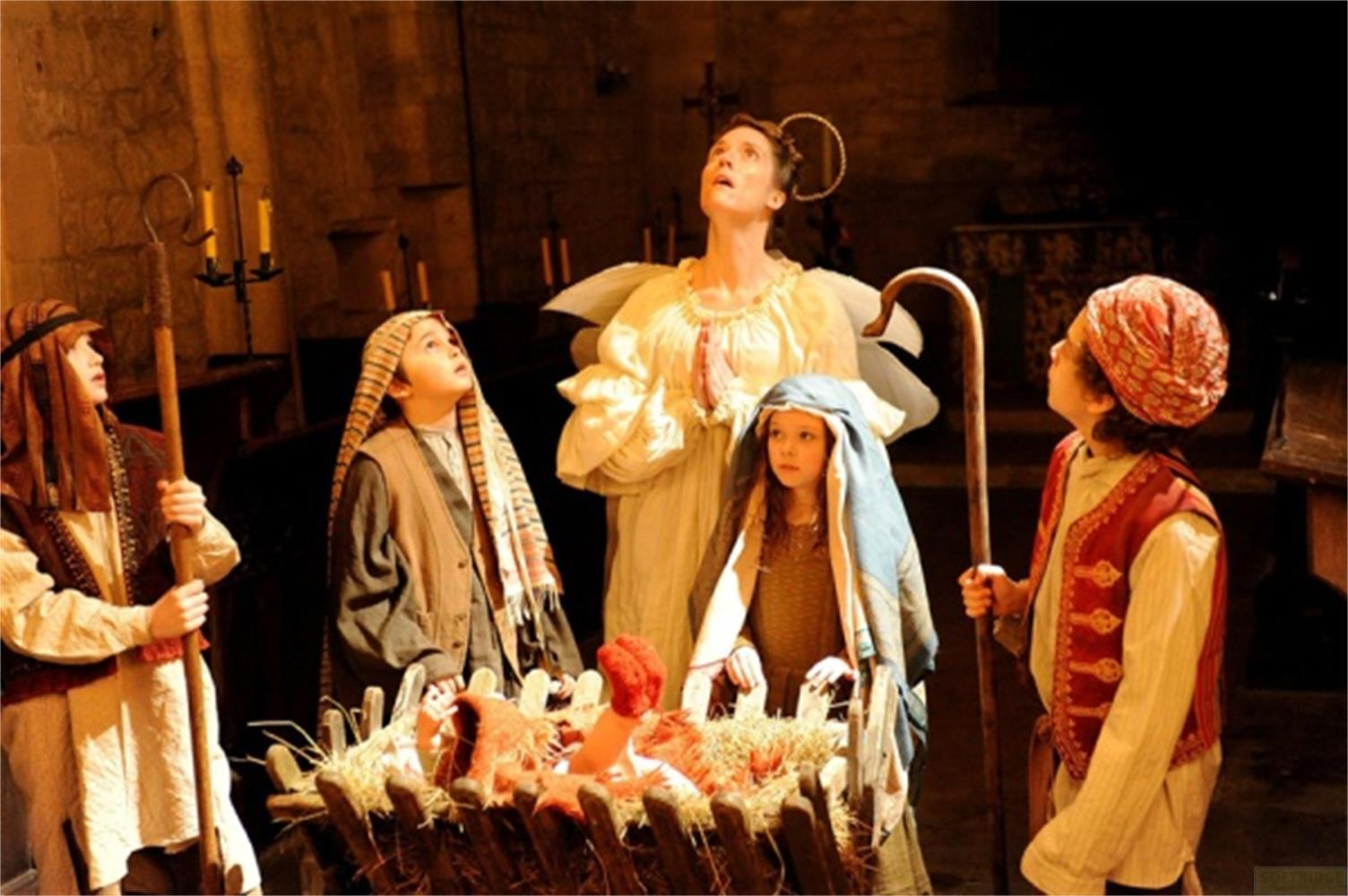 Scène de la Nativité avec des enfants déguisés en bergers et un ange regardant vers le haut.