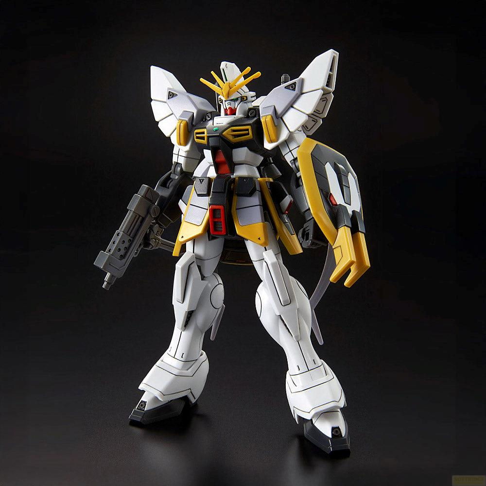 Un robot Gundam blanc et gris aux accents jaunes tient une arme.