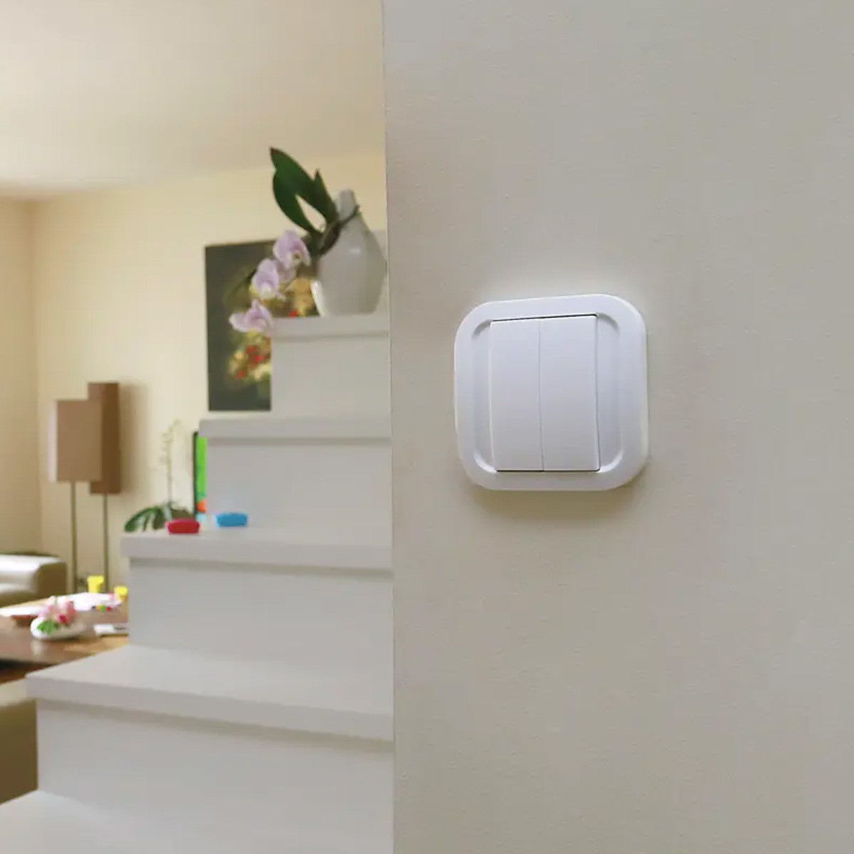Un interruttore della luce bianco con due pulsanti su un muro beige chiaro.
