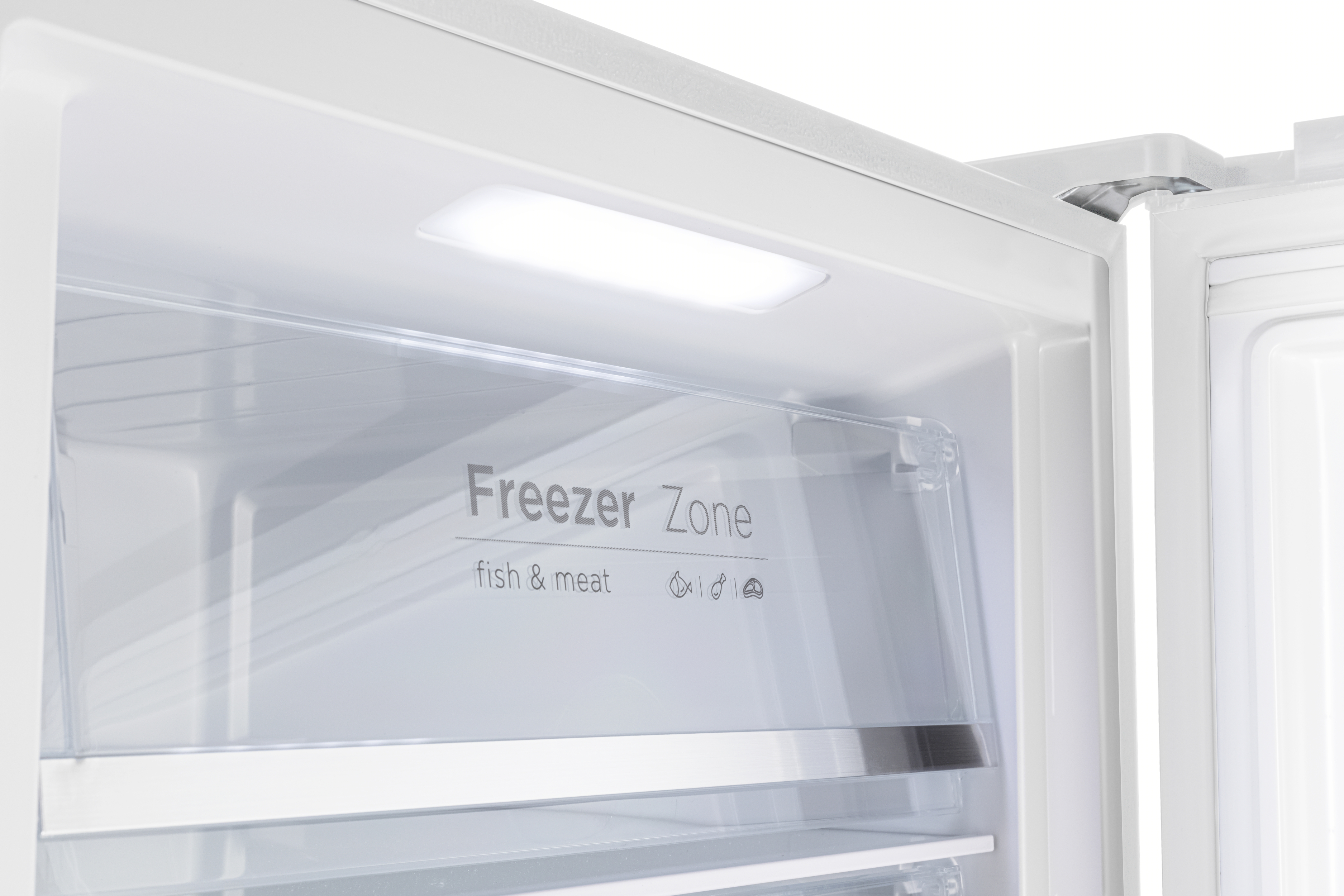 Innenansicht eines Kühlschranks mit einer Schublade mit der Aufschrift „Freezer Zone“.