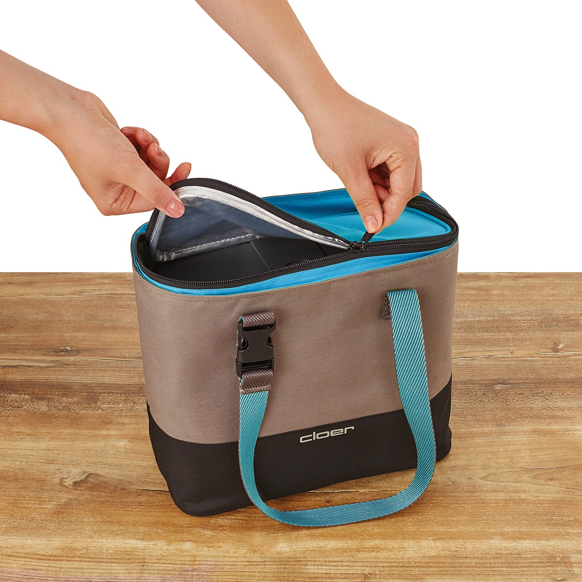 Eine graue und schwarze Kühltasche mit blauen Trägern und Reißverschluss wird geöffnet.
