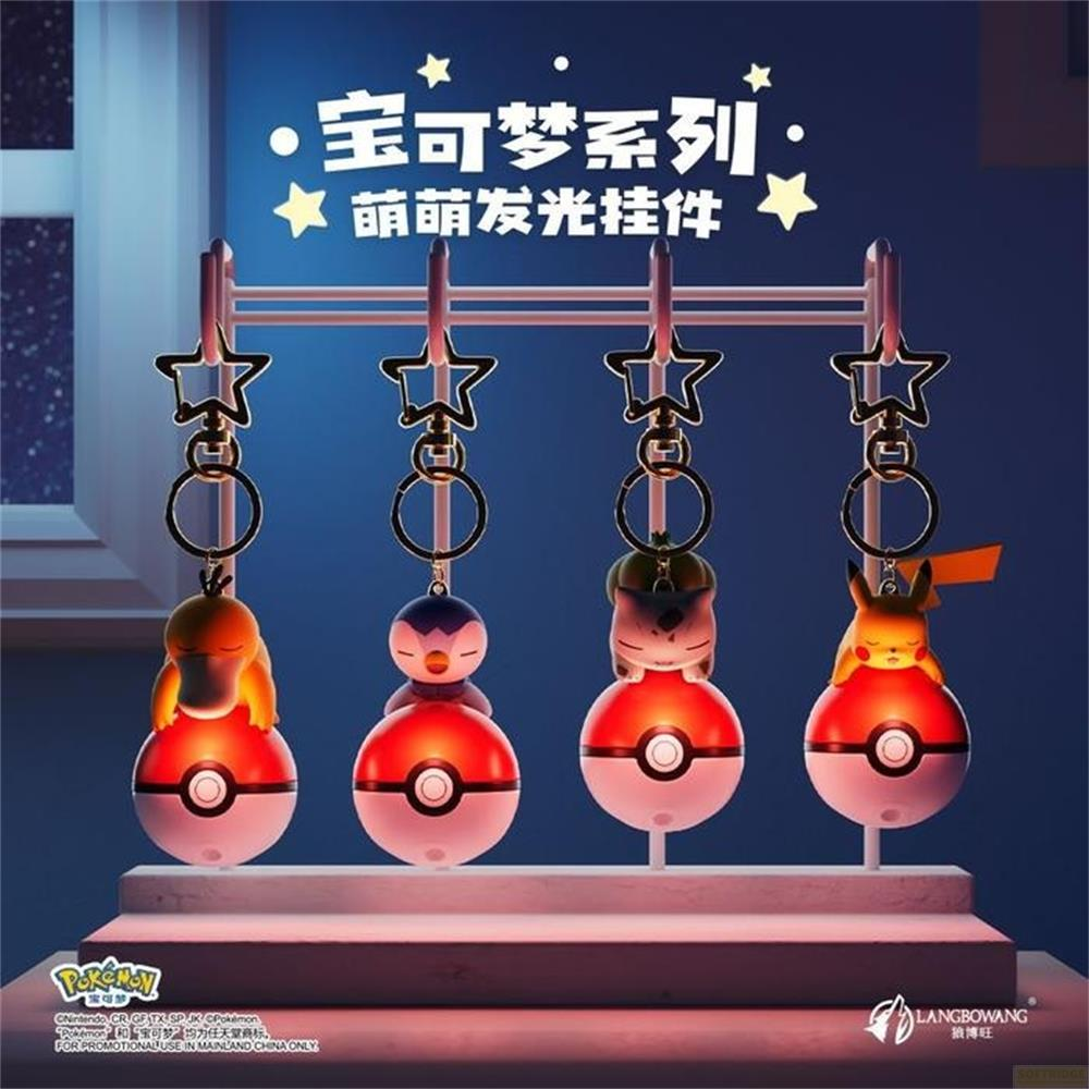 Quatre porte-clés Pokémon lumineux avec Poké Balls et étoiles sur fond sombre.