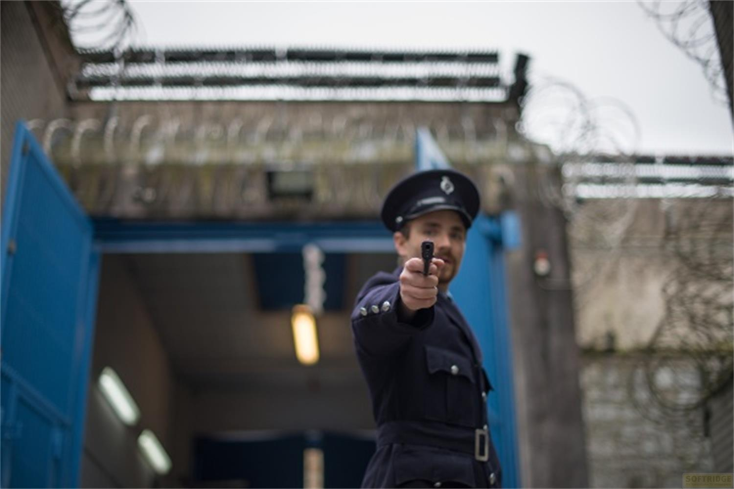Un uomo in uniforme punta una pistola verso lo spettatore.