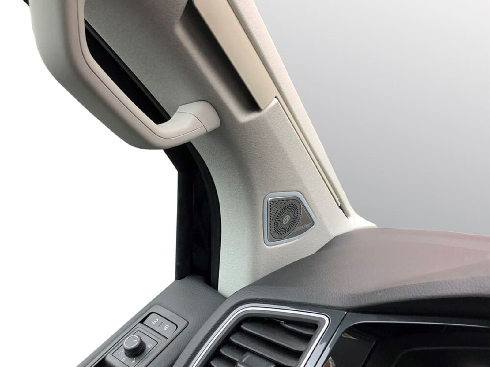 Ein Lautsprechergitter im Auto-Innenraum neben einem Griff.