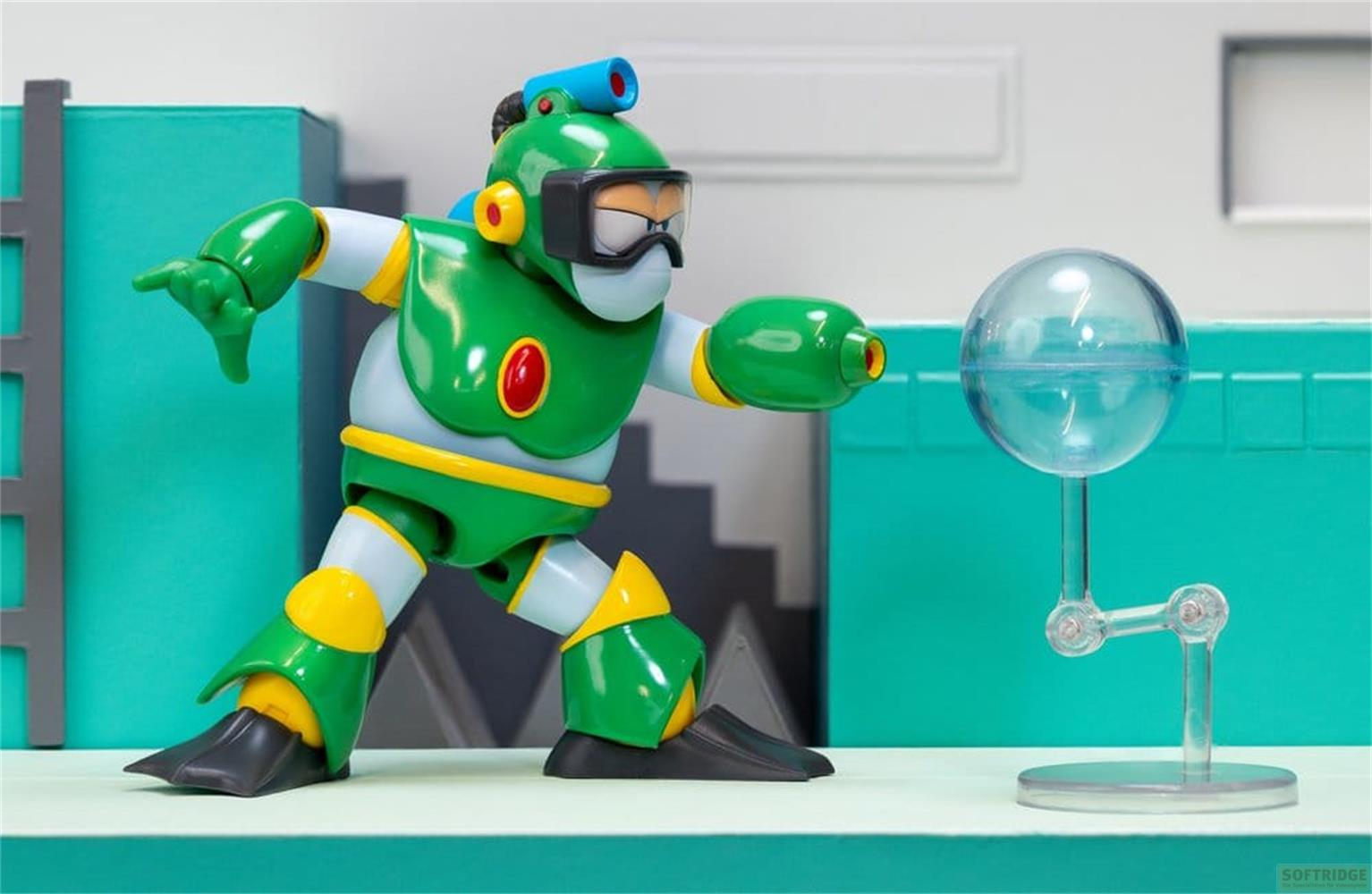 Ein grüner Roboter mit Schutzbrille und blauer Antenne steht vor einer transparenten Kugel.