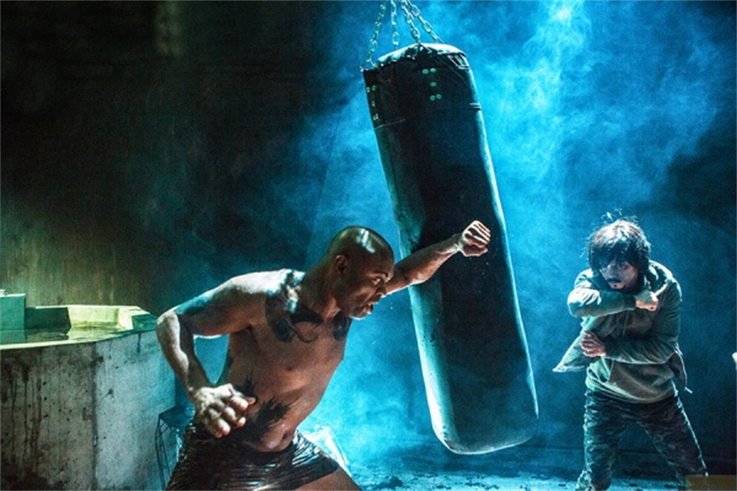 Un uomo colpisce un sacco da boxe mentre un altro uomo è vicino.