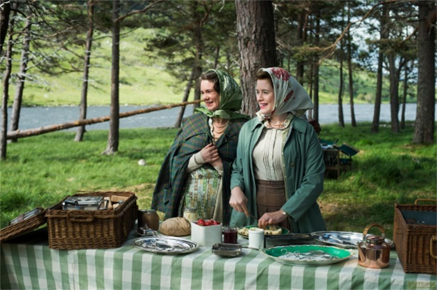 Due donne all'aperto a un picnic con un fiume sullo sfondo.