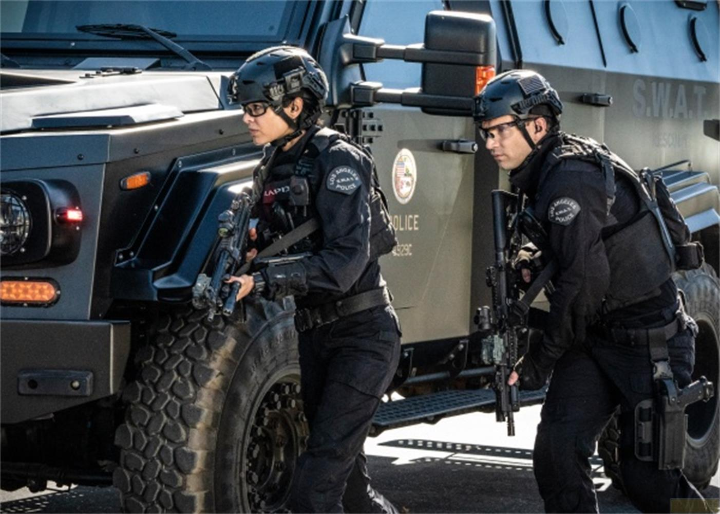 Due agenti SWAT in tenuta tattica accanto a un veicolo blindato.