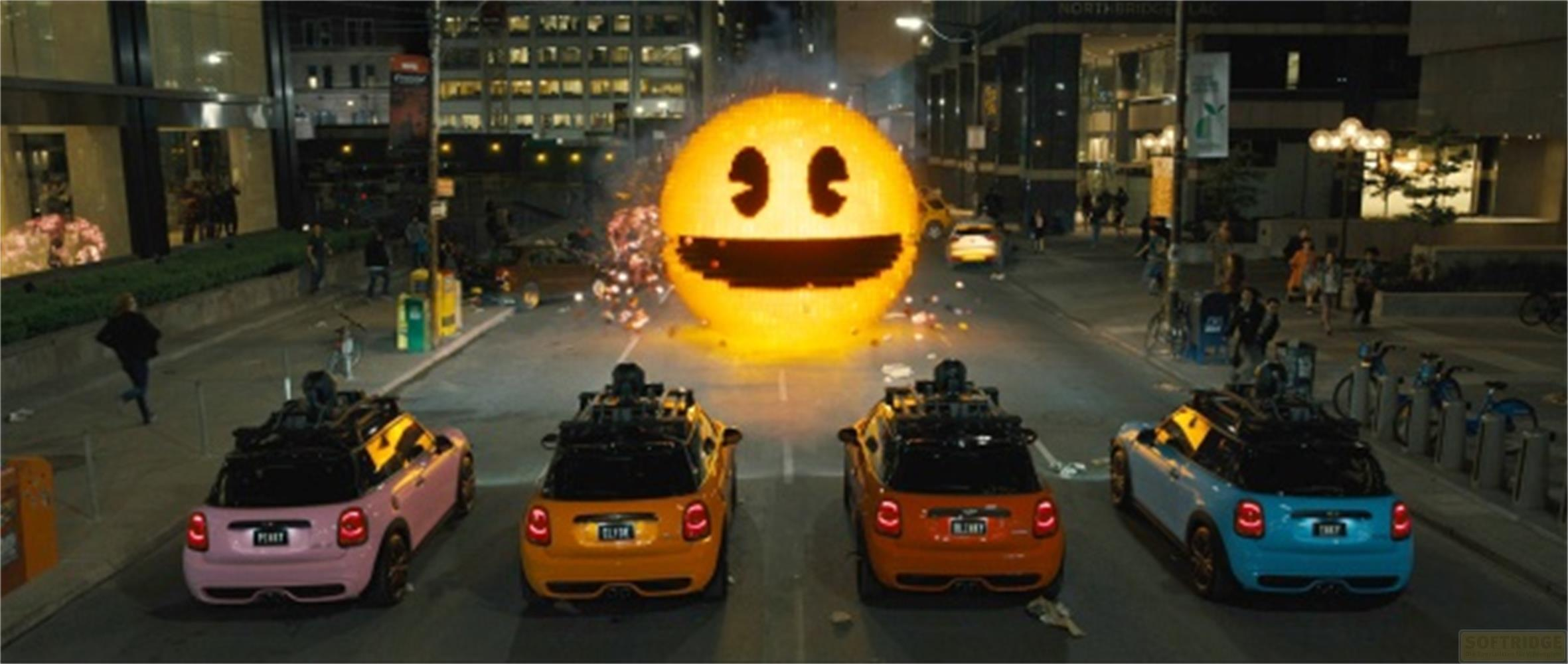 Vier Mini Coopers stehen auf einer Straße, während ein riesiger Pac-Man über ihnen schwebt.