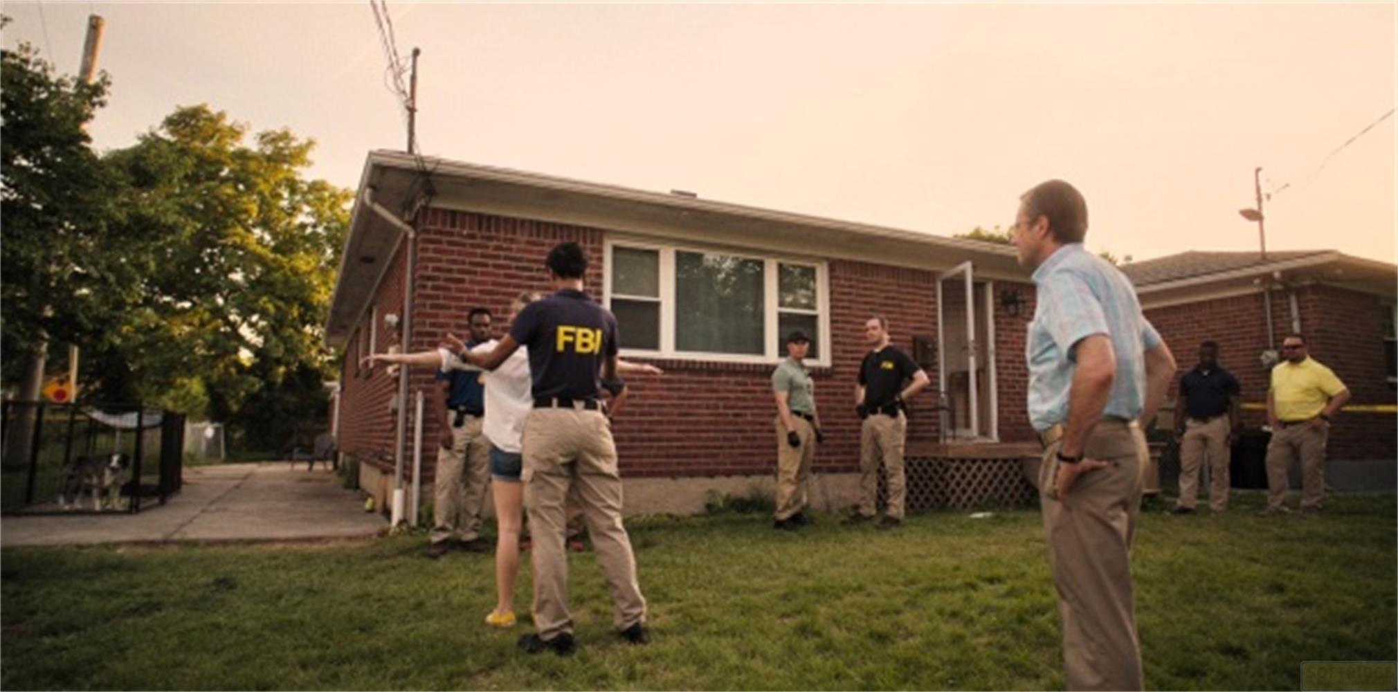 Agenti FBI e civili davanti a una casa di mattoni.