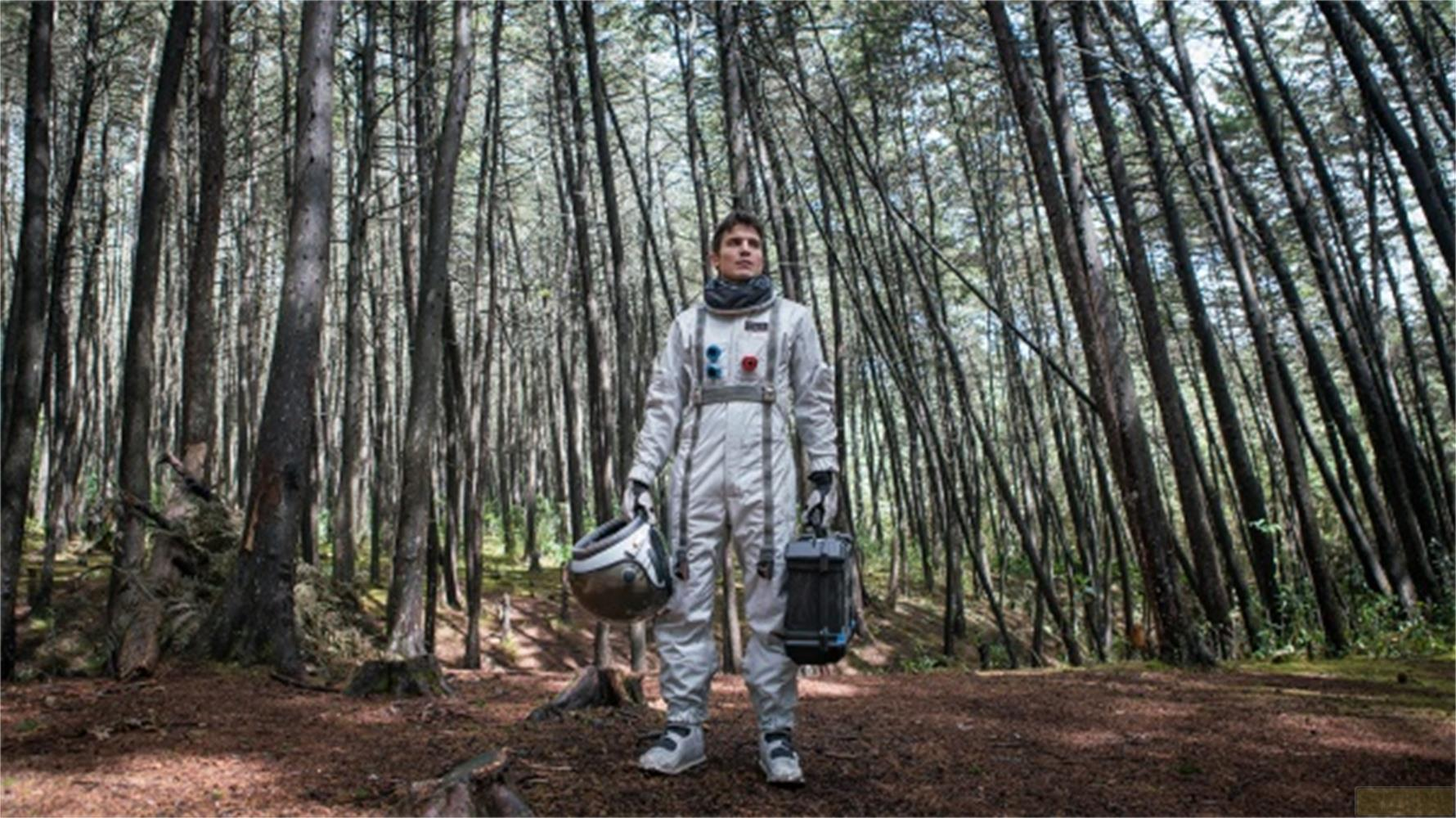 Un astronaute se tient dans une forêt d'arbres denses, tenant un casque et une mallette.