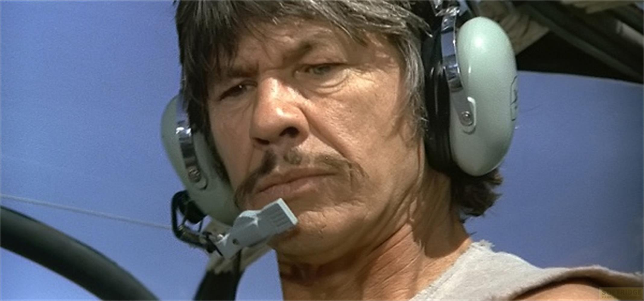 Un homme portant un casque et un microphone dans un cockpit par ciel clair.